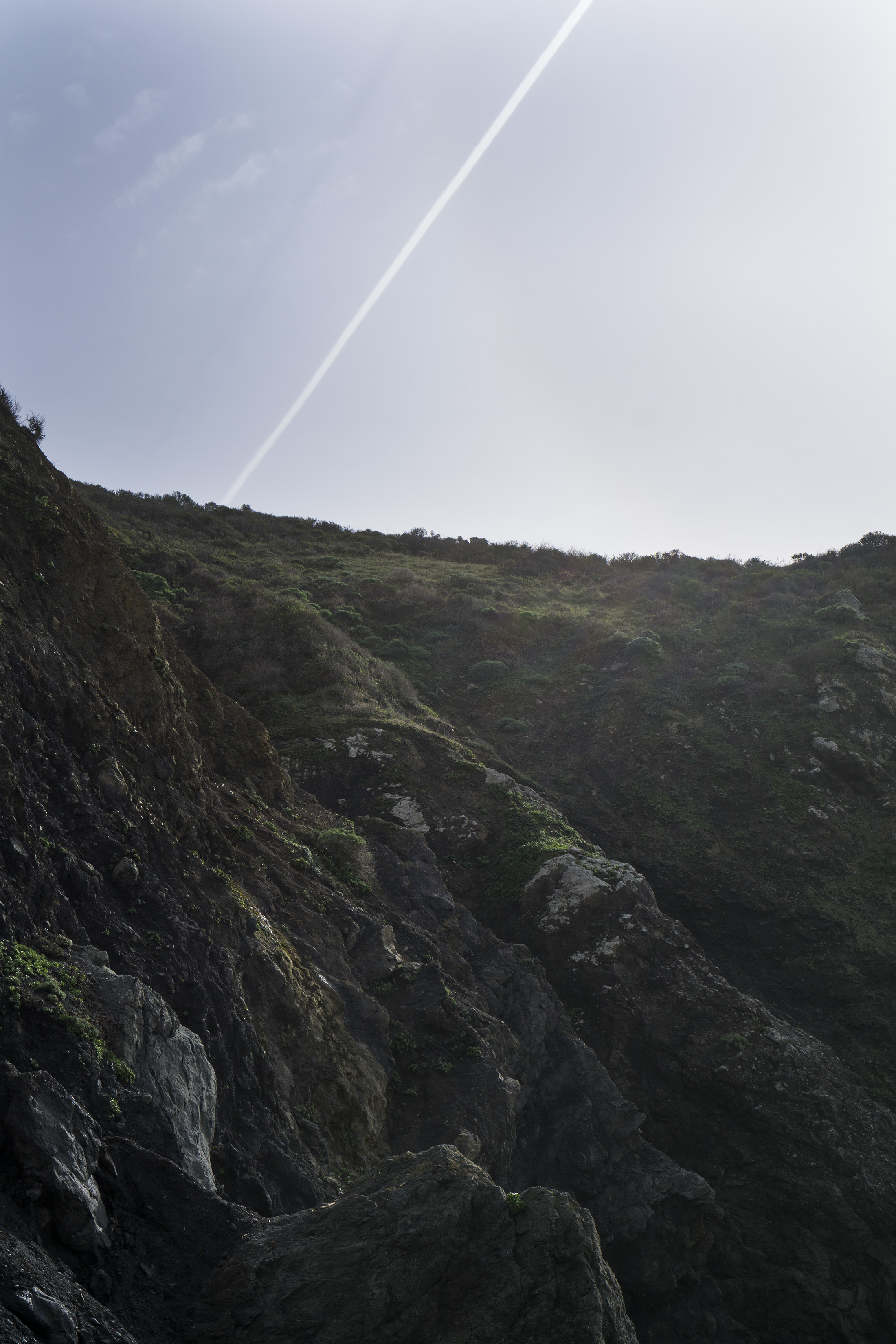Contrail in the sky behind the cliff at Pirates Cove, Marin Headlands, Golden Gate National Recreation Area / Darker than Green