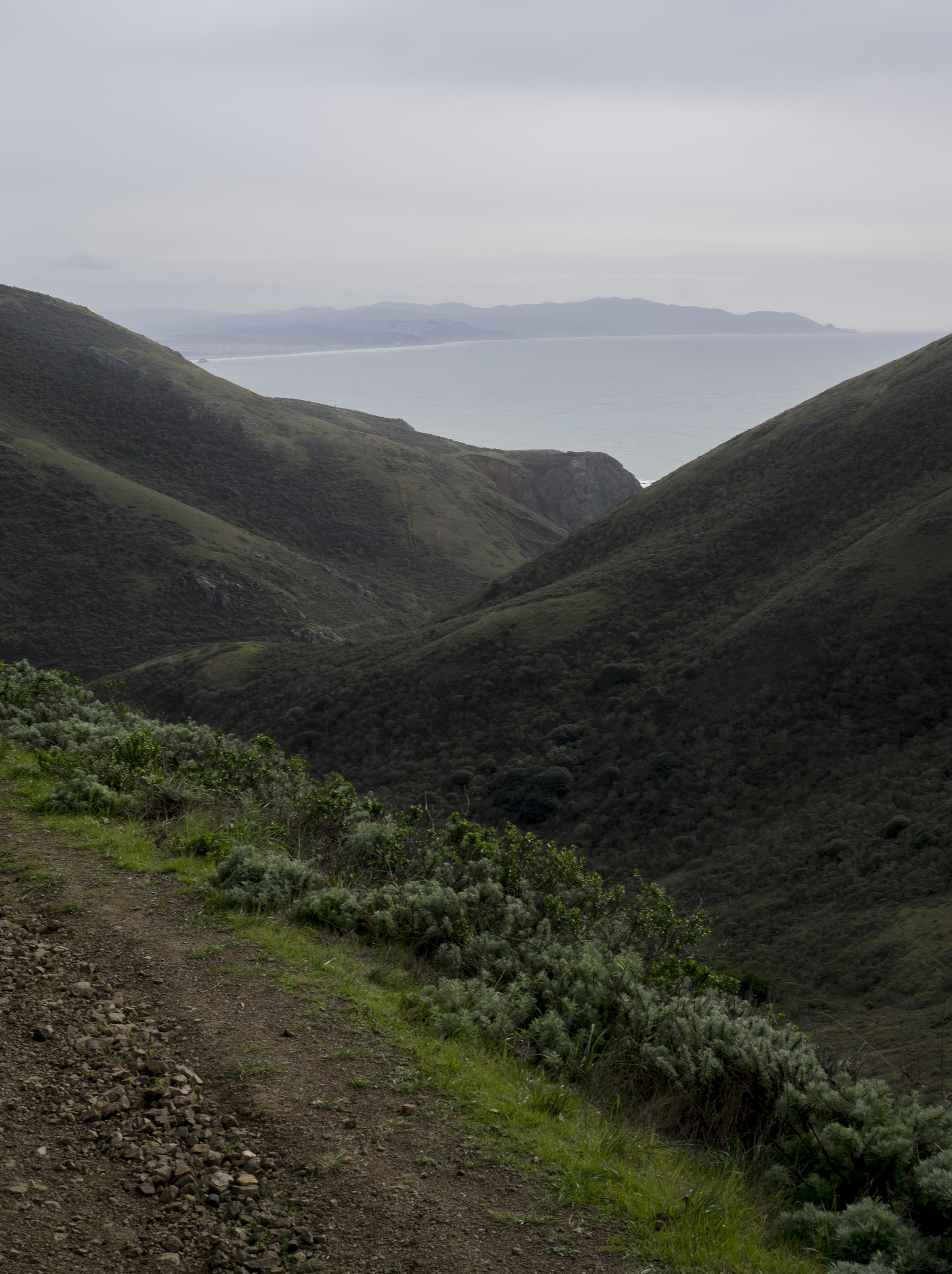 Pacific Ocean peeking through mountains along Tennessee Valley Trail, Marin Headlands, Golden Gate National Recreation Area / Darker than Green