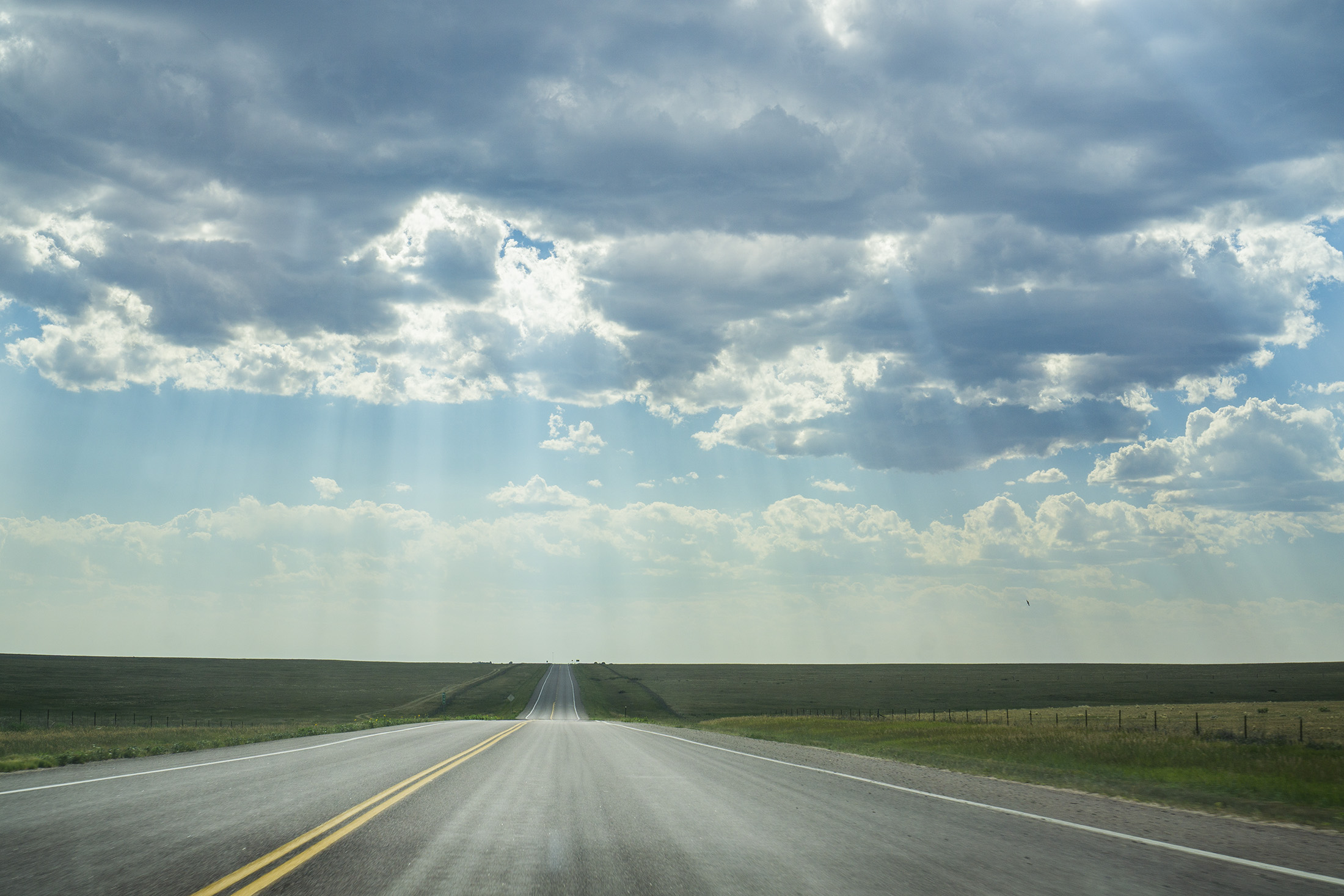 Sun shining through the clouds onto the open road / Darker than Green